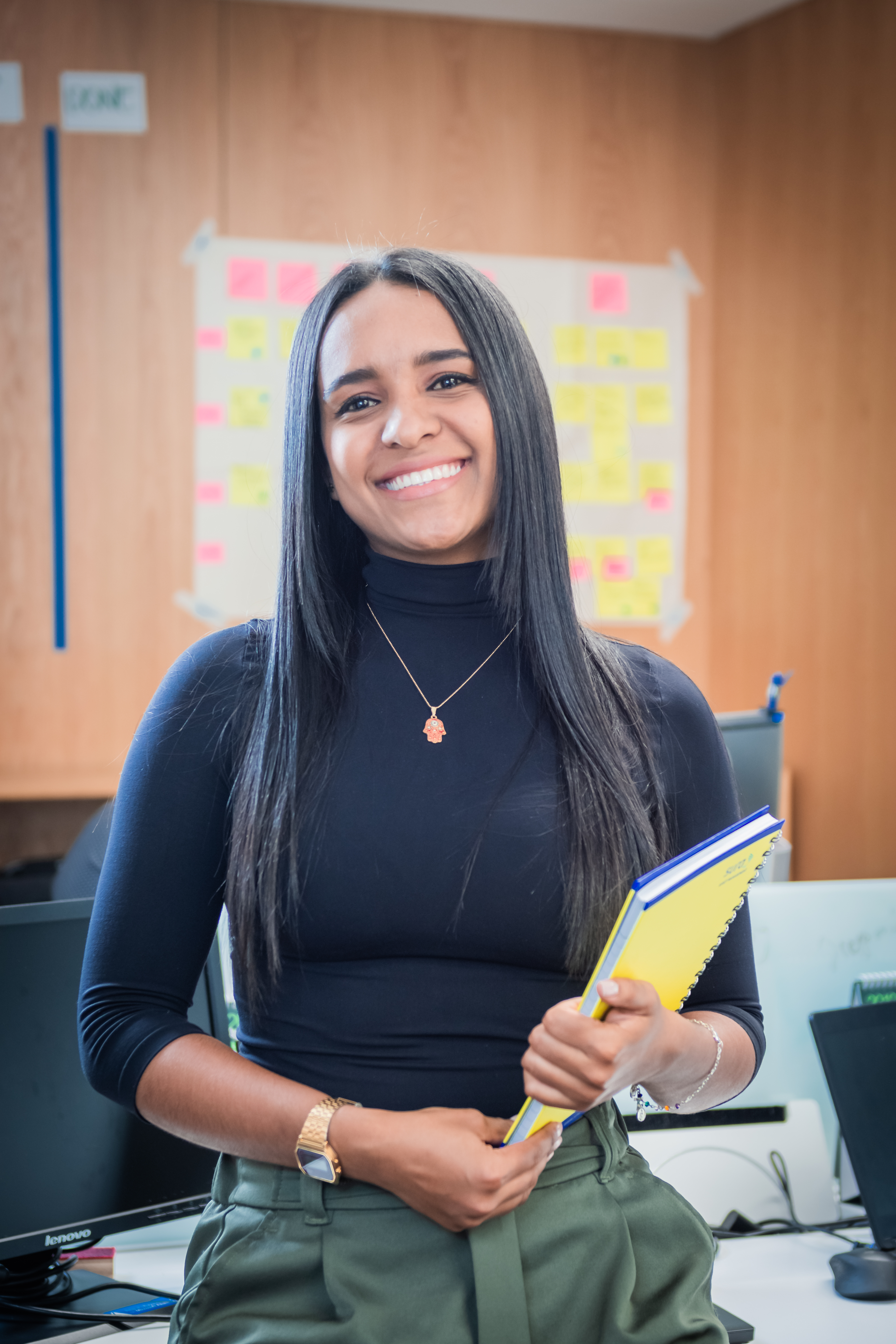 Mujer sonriendo sosteniendo un cuaderno